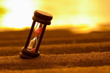 21259213 - closeup of hourglass on the sand timer beach sunrise